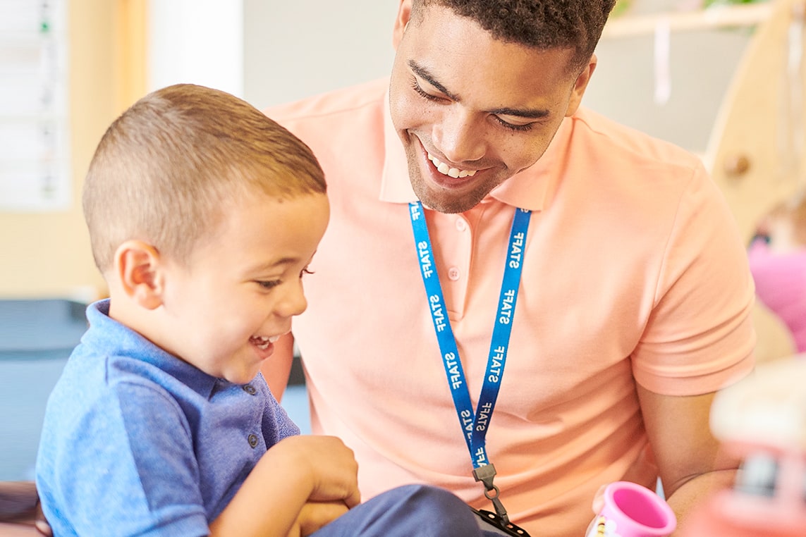 Teacher showing student a toy and smiling