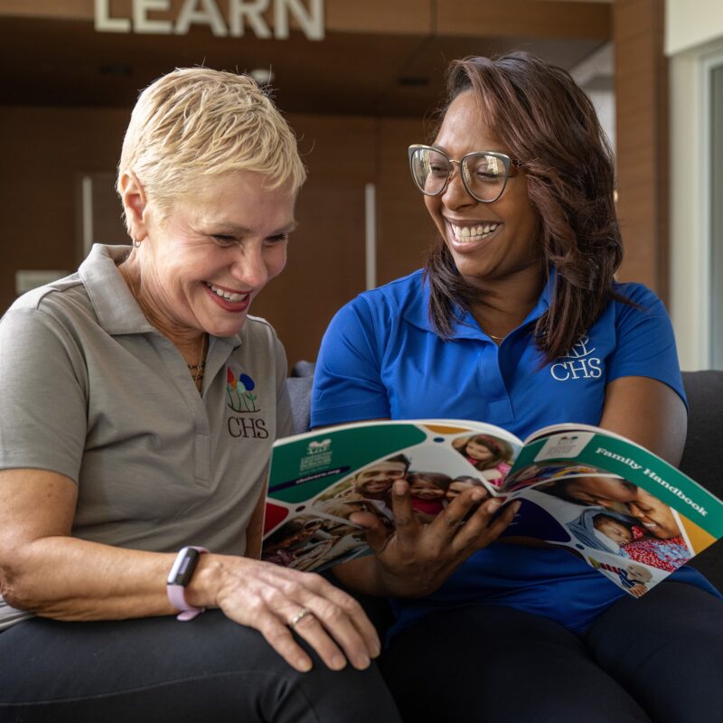 Two people reading the CHS Family Handbook