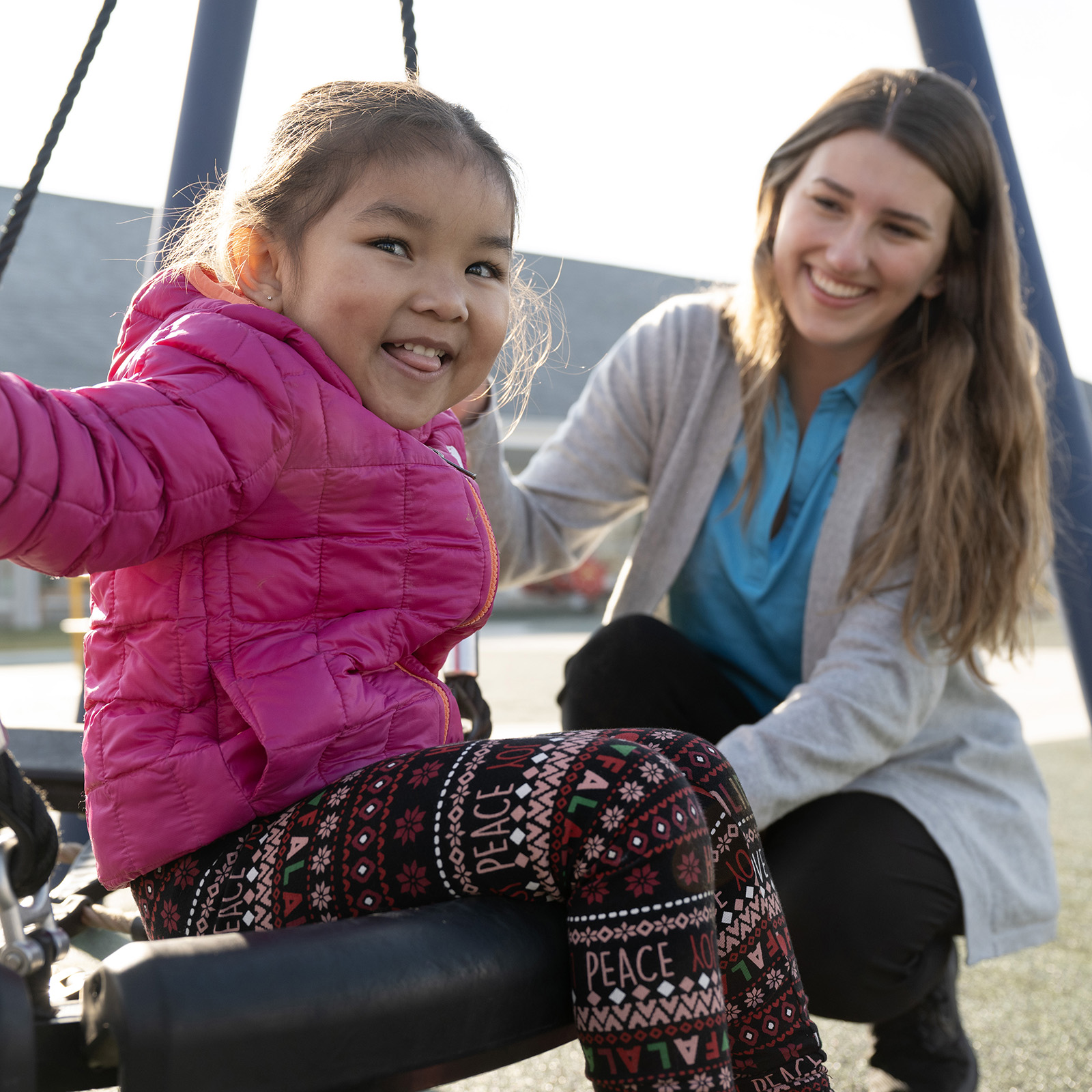 Teacher standing next to a student on a tire swing