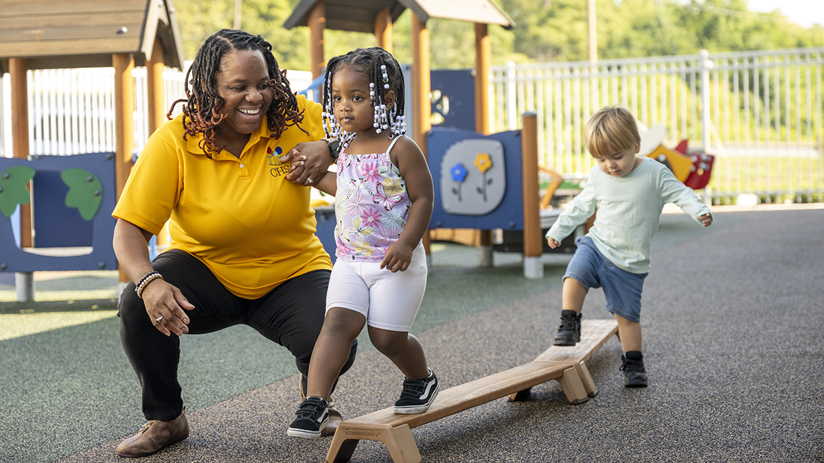 Teacher working with a student to color with crayons