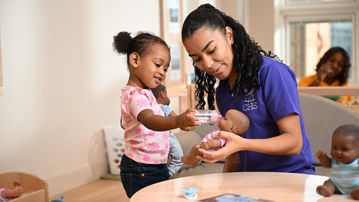 Teacher working with a student to color with crayons